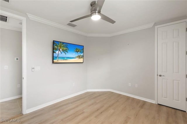 spare room with ceiling fan, visible vents, light wood-style floors, baseboards, and crown molding