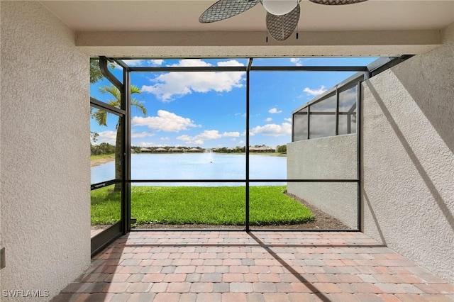 unfurnished sunroom featuring ceiling fan and a water view