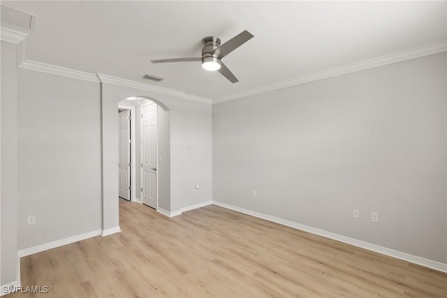 spare room featuring arched walkways, visible vents, baseboards, light wood-type flooring, and crown molding