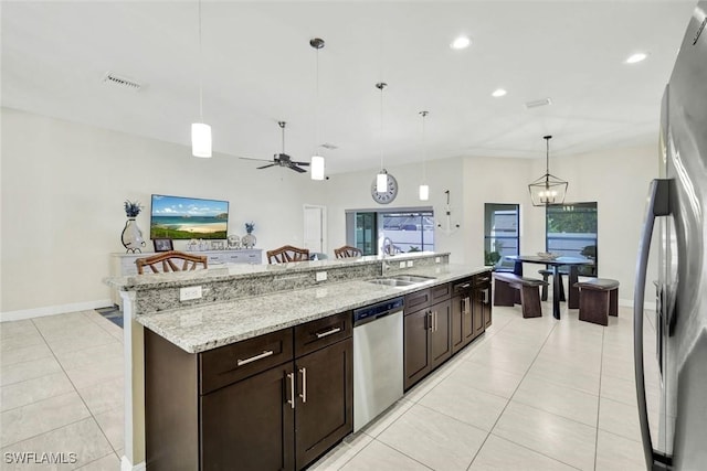 kitchen with light tile patterned floors, stainless steel appliances, a sink, visible vents, and an island with sink