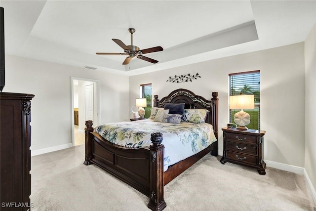 bedroom featuring light carpet, a raised ceiling, visible vents, and baseboards