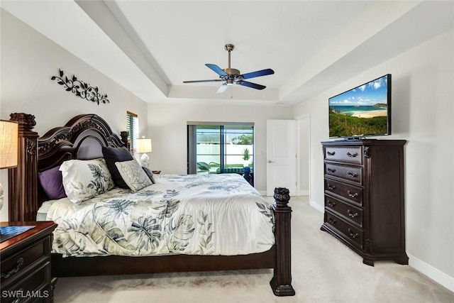 bedroom featuring light carpet, baseboards, ceiling fan, access to outside, and a tray ceiling