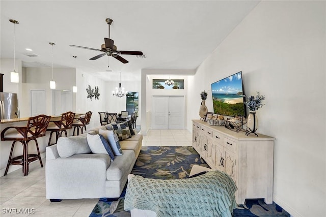 living room featuring ceiling fan with notable chandelier, baseboards, and light tile patterned floors