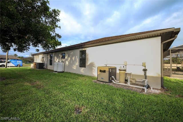 rear view of house featuring a yard, stucco siding, and central air condition unit