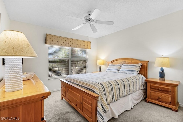 bedroom with light carpet, a ceiling fan, and a textured ceiling