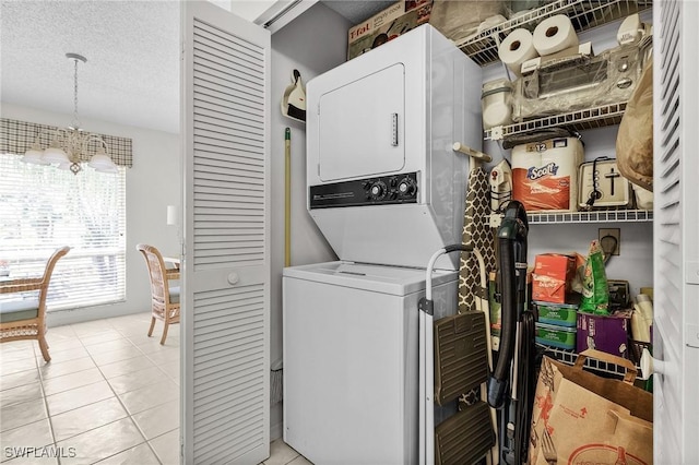 washroom featuring stacked washer / drying machine, laundry area, a textured ceiling, and light tile patterned floors