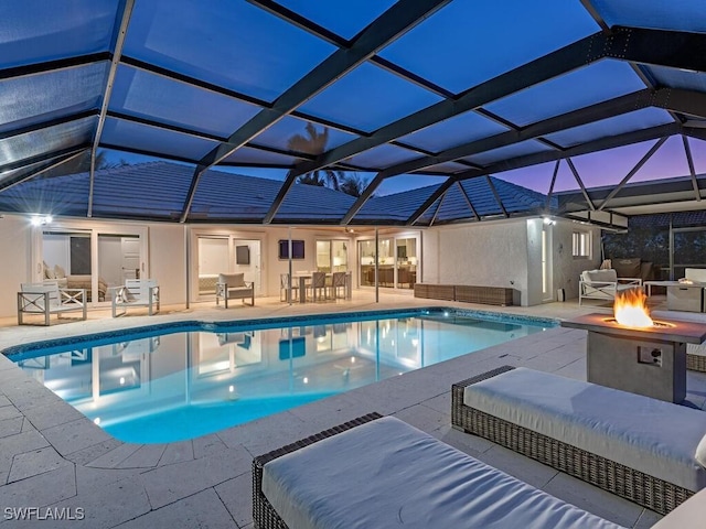 pool with a lanai, an outdoor living space with a fire pit, and a patio