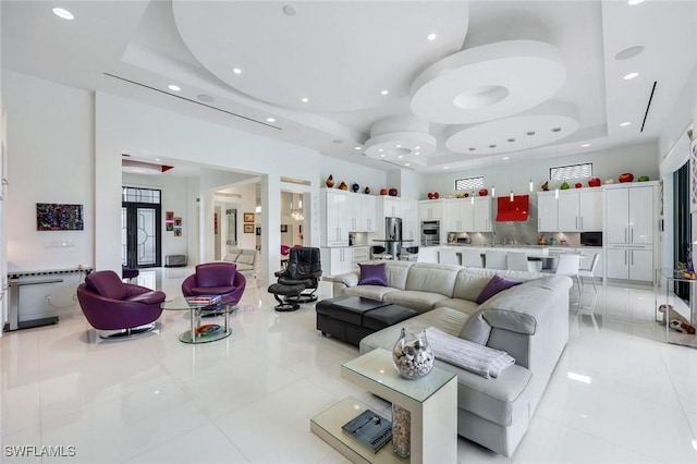 living room with light tile patterned floors, recessed lighting, a high ceiling, and a tray ceiling