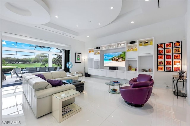 living room with baseboards, light tile patterned floors, recessed lighting, a high ceiling, and a raised ceiling