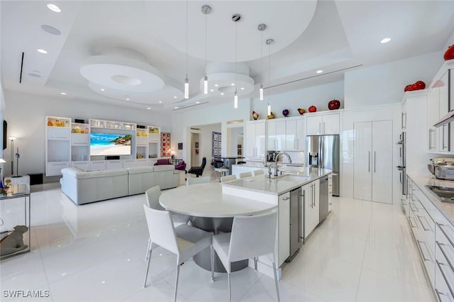 kitchen with a tray ceiling, black electric stovetop, stainless steel fridge, and white cabinets