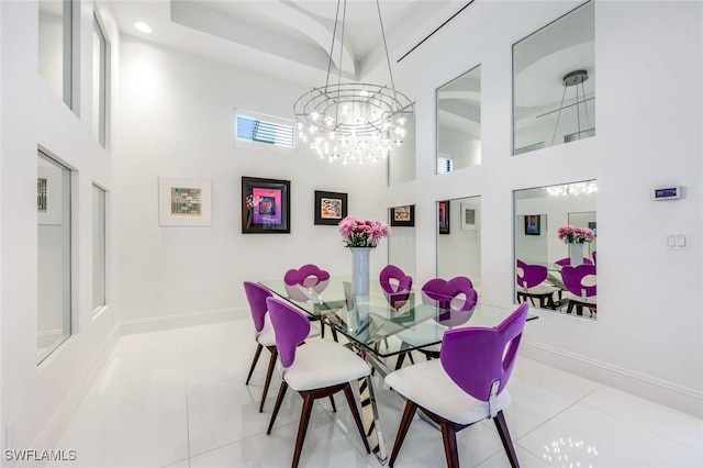 tiled dining area with a tray ceiling, a high ceiling, and baseboards