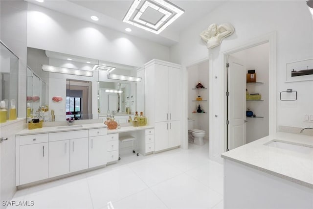 bathroom with two vanities, toilet, and a sink