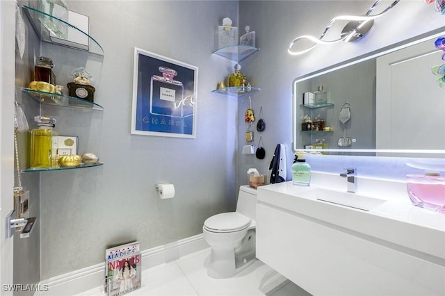 half bath featuring tile patterned flooring, toilet, vanity, and baseboards