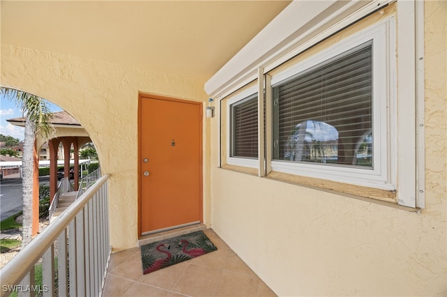 view of exterior entry with a balcony and stucco siding