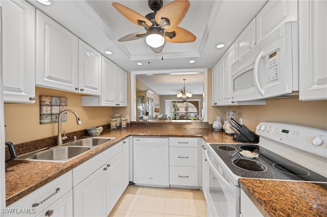 kitchen featuring dark countertops, white appliances, a tray ceiling, and a sink