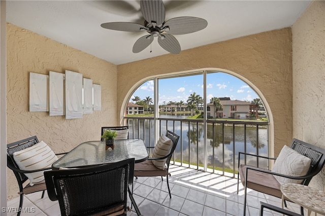 balcony with outdoor dining area, a water view, and ceiling fan