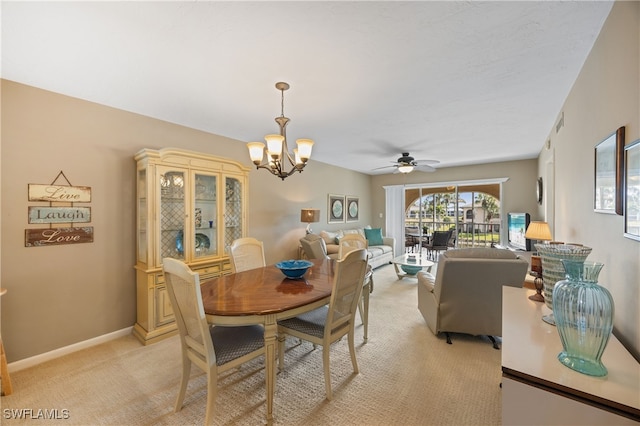 dining room featuring light carpet, ceiling fan with notable chandelier, and baseboards