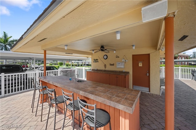 view of patio / terrace with outdoor wet bar, fence, and ceiling fan