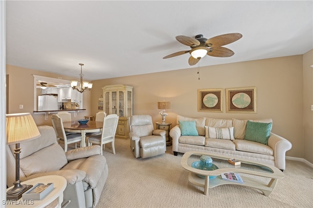 living room featuring light carpet, baseboards, and ceiling fan with notable chandelier