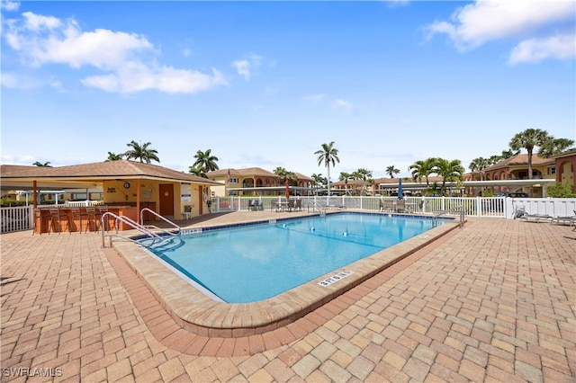 community pool with a patio area and fence