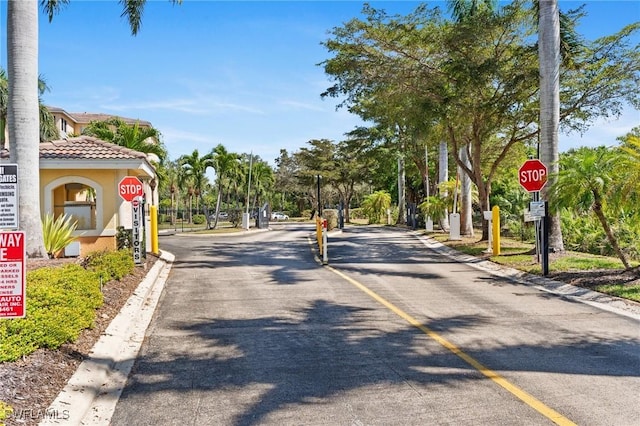 view of street with traffic signs, curbs, and a gated entry