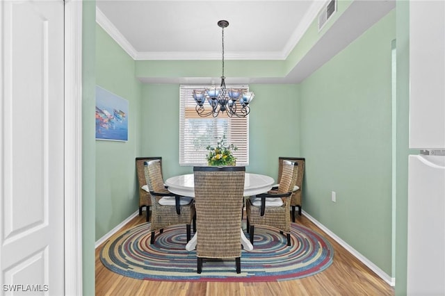 dining room featuring a chandelier, wood finished floors, visible vents, and crown molding