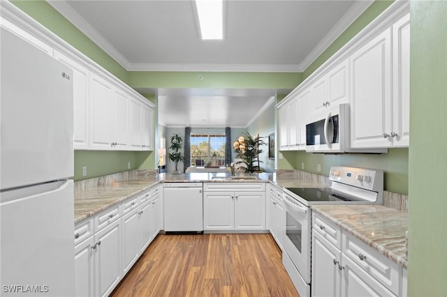 kitchen with white appliances, ornamental molding, light wood-style floors, white cabinetry, and a sink