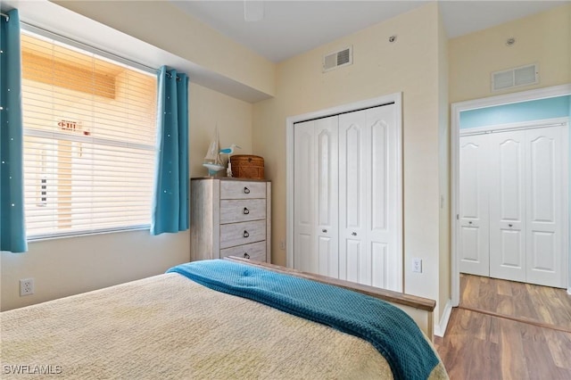 bedroom with a closet, visible vents, and wood finished floors