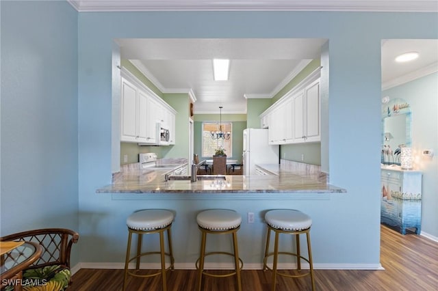 kitchen featuring a sink, white appliances, dark wood-style floors, and crown molding