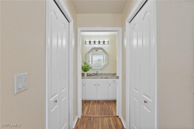 corridor featuring a sink and wood finished floors