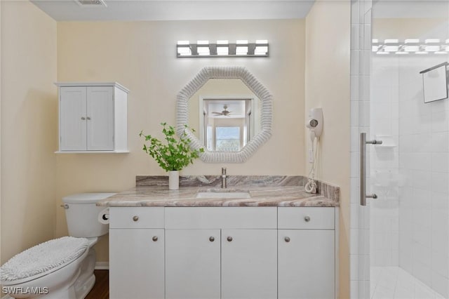 full bathroom with visible vents, a tile shower, vanity, and toilet