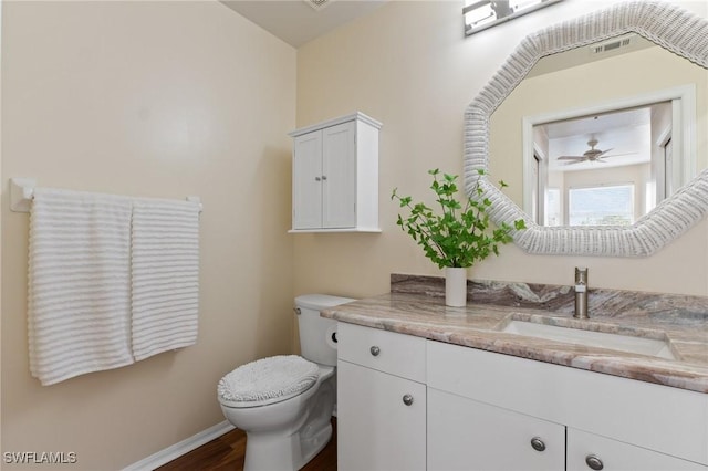 half bath featuring toilet, wood finished floors, visible vents, vanity, and baseboards