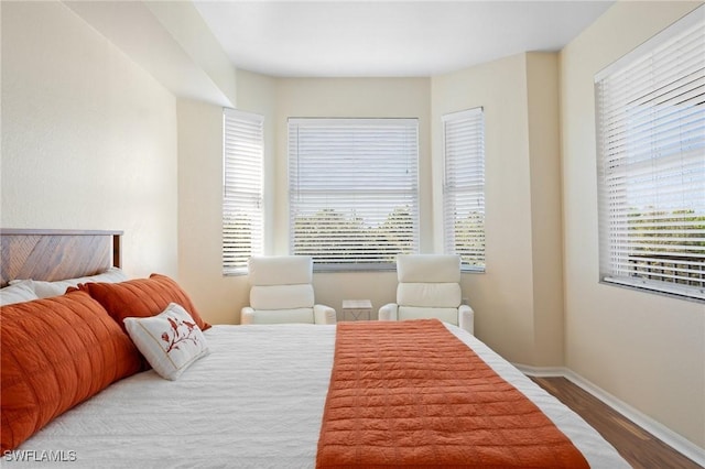 bedroom featuring multiple windows, baseboards, and wood finished floors