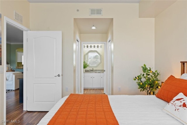 unfurnished bedroom with a sink, dark wood-style floors, visible vents, and connected bathroom