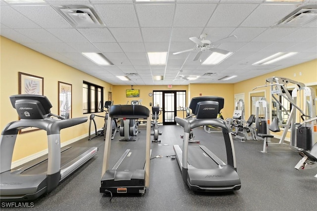 gym with a paneled ceiling, baseboards, visible vents, and ceiling fan