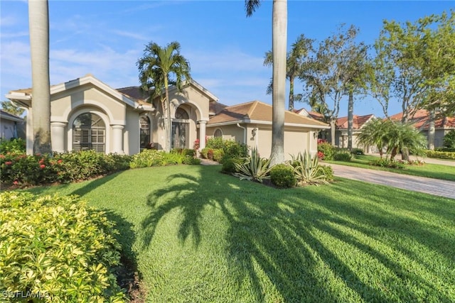 mediterranean / spanish home with a garage, a front yard, driveway, and stucco siding