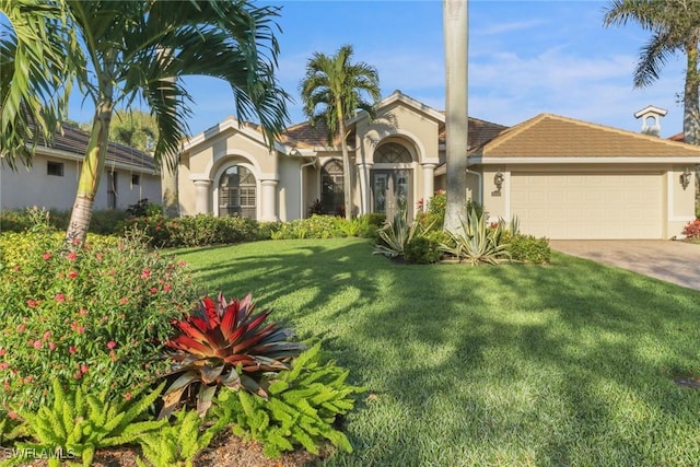 mediterranean / spanish-style house with driveway, a front yard, an attached garage, and stucco siding