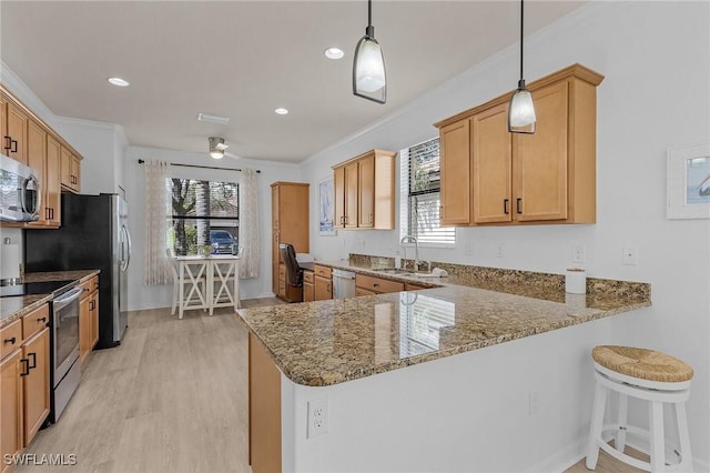 kitchen with stone counters, light wood-style flooring, appliances with stainless steel finishes, ornamental molding, and a sink