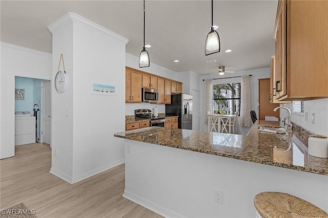 kitchen with stainless steel appliances, a peninsula, a sink, washer / dryer, and crown molding