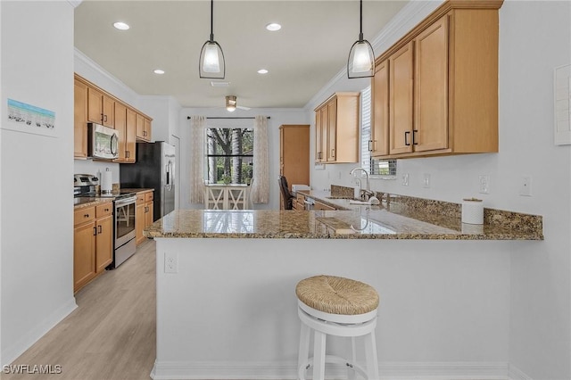 kitchen featuring appliances with stainless steel finishes, ornamental molding, a sink, light stone countertops, and a peninsula