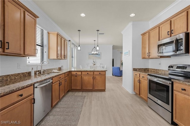 kitchen with appliances with stainless steel finishes, crown molding, a sink, and a peninsula