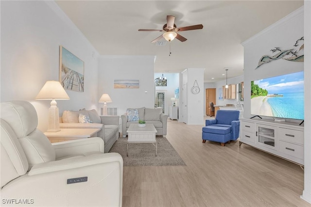 living area featuring ceiling fan with notable chandelier, crown molding, visible vents, and light wood-style floors