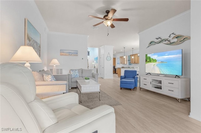 living area featuring light wood-style floors, a ceiling fan, and crown molding