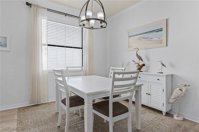 dining room with light wood-style floors, a notable chandelier, baseboards, and ornamental molding