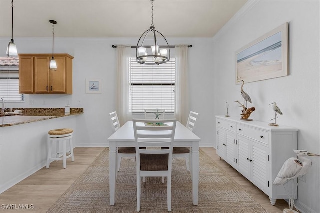 dining room with a chandelier, light wood-type flooring, and baseboards