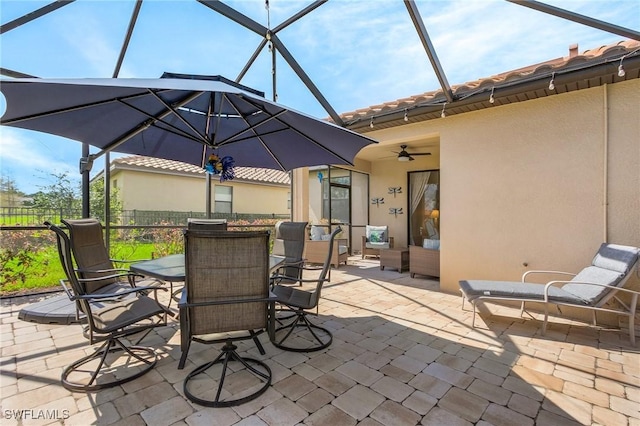 view of patio featuring outdoor dining area, a lanai, fence, an outdoor living space, and a ceiling fan