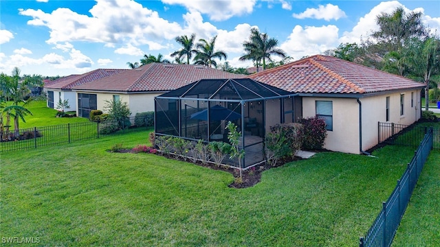 back of property featuring glass enclosure, a fenced backyard, a tiled roof, a yard, and stucco siding