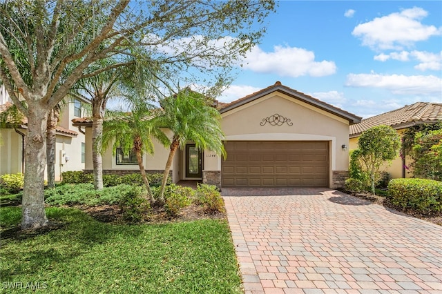 mediterranean / spanish-style home featuring a garage, brick siding, a tile roof, decorative driveway, and stucco siding