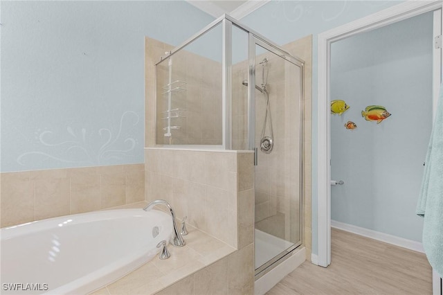 bathroom with wood finished floors, a shower stall, baseboards, and a bath