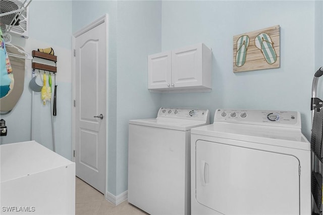 clothes washing area featuring cabinet space, washing machine and dryer, light tile patterned floors, and baseboards